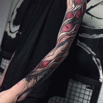 Mustvalge varrukatätoveering punaste aktsentidega käsivarrel