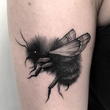 Detailed blackwork bumblebee tattoo with textured body and transparent wings
