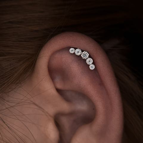 Mitmekordne helix-piercing - neli ehet kõrva ülemises kõhres moodustavad efektse ja harmoonilise rea. Täpne paigutus, steriilne teostus ja hoolikas paranemine.